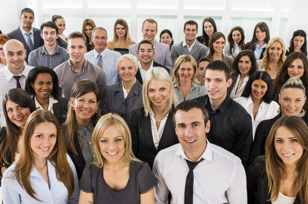 High angle view of large group of smiling business people standing and looking at the camera.
